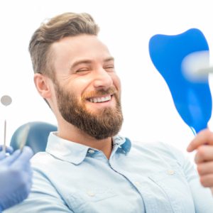 Young man looking at his new smile in a mirror