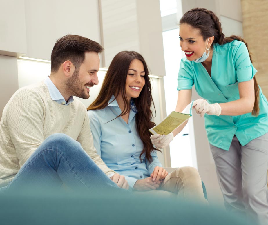 Dentist showing two patients services they offer.