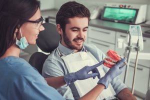 dentist showing patient model of teeth